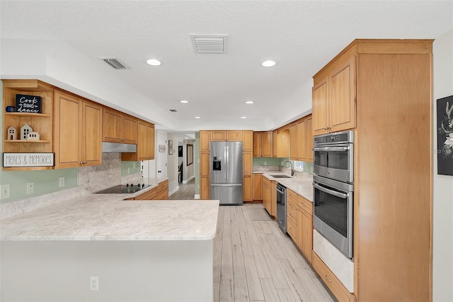 kitchen with sink, light hardwood / wood-style flooring, a textured ceiling, kitchen peninsula, and stainless steel appliances