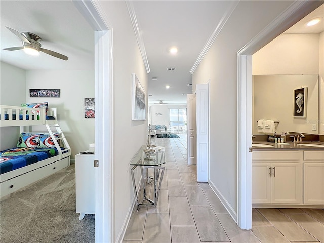 corridor featuring light colored carpet, crown molding, and sink