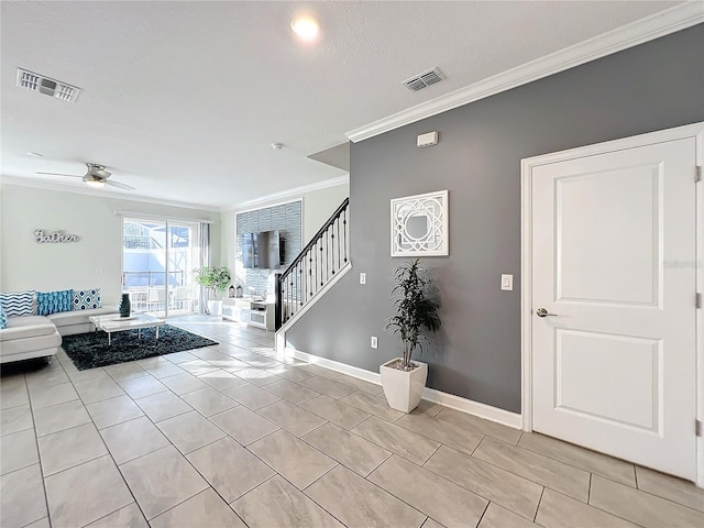 tiled foyer entrance featuring a textured ceiling, ceiling fan, and ornamental molding