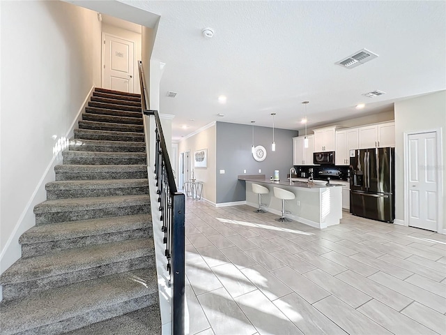 staircase with crown molding and sink