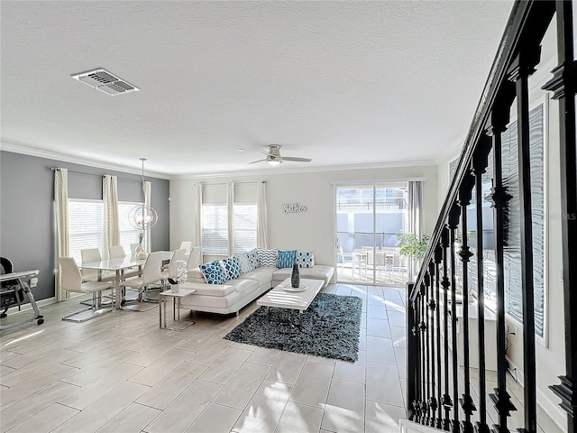 living room with ceiling fan with notable chandelier, a textured ceiling, and crown molding