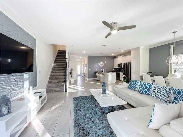 living room featuring crown molding, sink, light tile patterned flooring, and ceiling fan