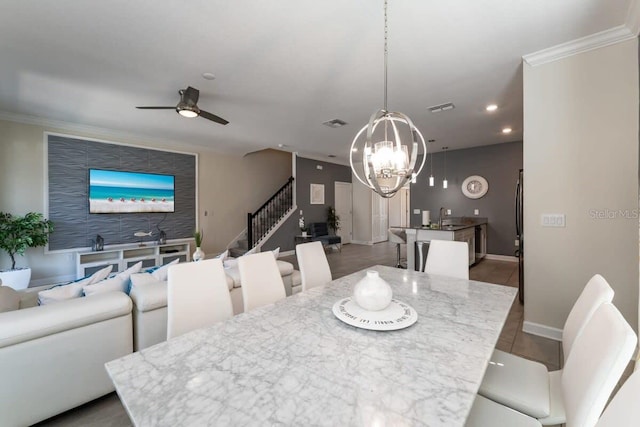 dining room with crown molding, sink, hardwood / wood-style floors, and ceiling fan with notable chandelier