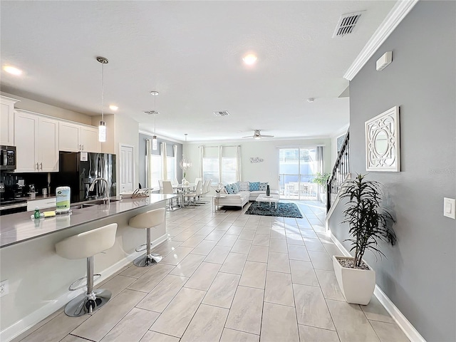 kitchen featuring a kitchen breakfast bar, appliances with stainless steel finishes, ceiling fan, decorative light fixtures, and white cabinets