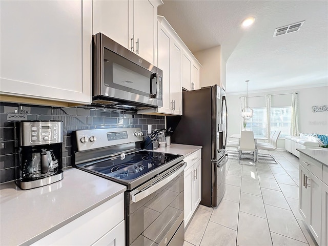 kitchen featuring white cabinets, appliances with stainless steel finishes, decorative backsplash, and light tile patterned floors