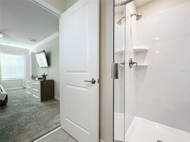 bathroom with tiled shower and crown molding