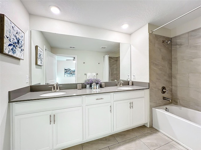 bathroom featuring a textured ceiling, tile patterned flooring, vanity, and tiled shower / bath combo