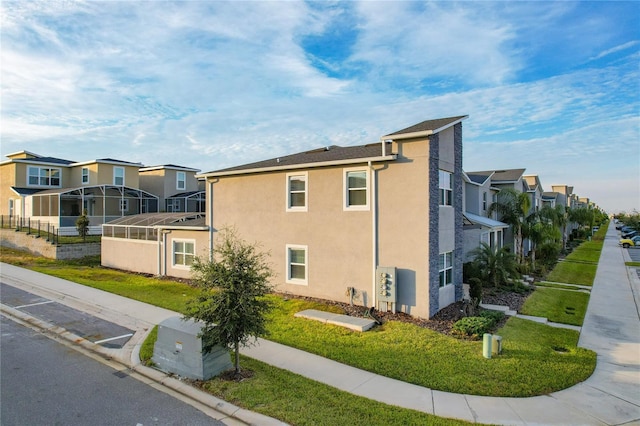 view of side of property with a yard and a lanai