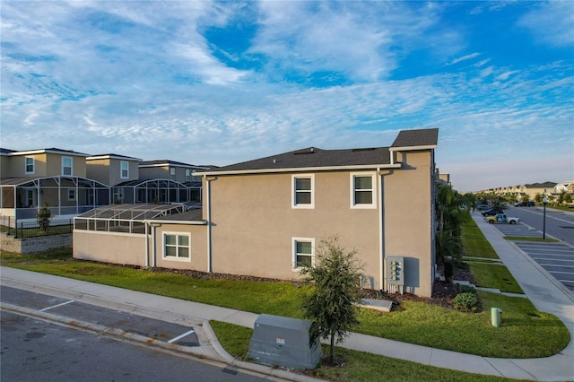 view of side of property featuring a lanai and a yard