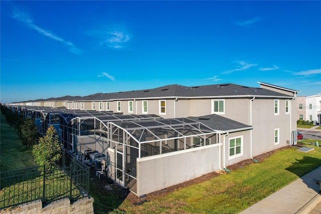 back of house with a lawn and glass enclosure