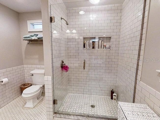 bathroom with an enclosed shower, tile walls, and toilet