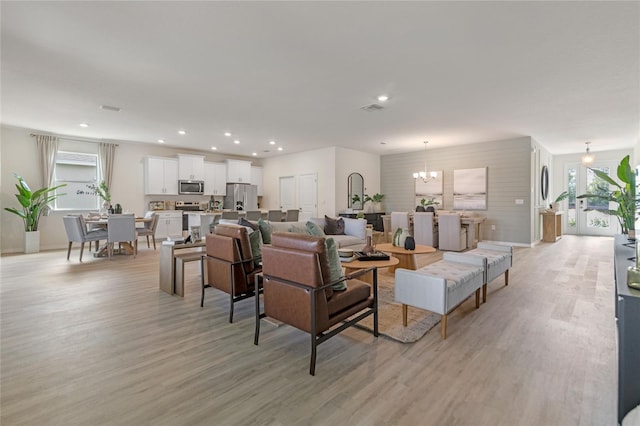 living room with an inviting chandelier and light wood-type flooring