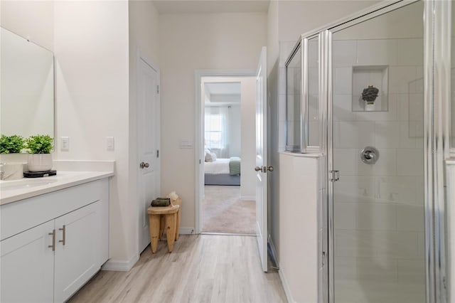 bathroom with a shower with door, vanity, and wood-type flooring