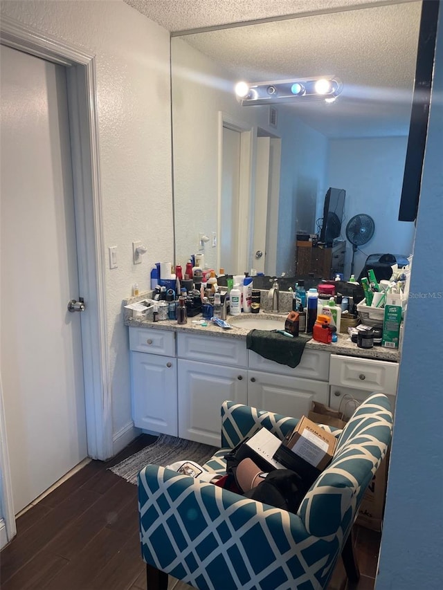 bathroom with hardwood / wood-style floors, vanity, and a textured ceiling