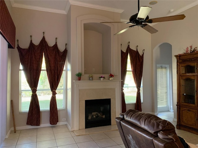 living room with crown molding, ceiling fan, a high end fireplace, and light tile patterned floors