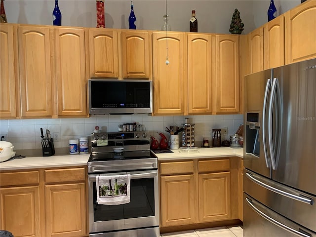 kitchen with backsplash, light tile patterned flooring, and appliances with stainless steel finishes