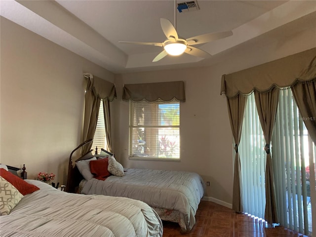 bedroom featuring ceiling fan, dark parquet flooring, and a raised ceiling