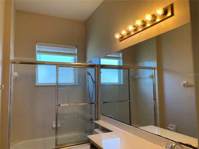 bathroom featuring vanity, a wealth of natural light, and bath / shower combo with glass door