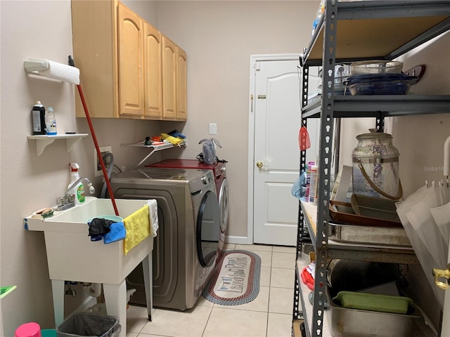 laundry room with light tile patterned flooring, cabinets, washer and clothes dryer, and sink