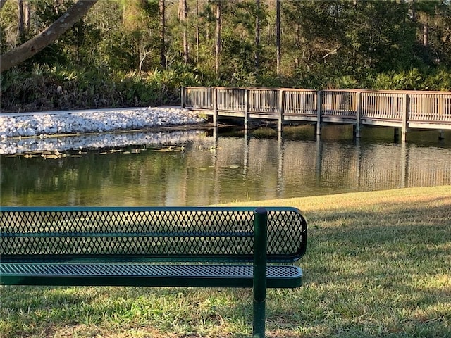 view of dock with a water view and a lawn