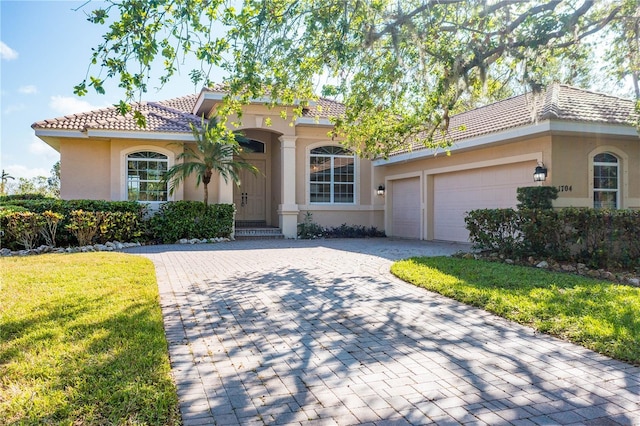 mediterranean / spanish-style house featuring a garage and a front lawn