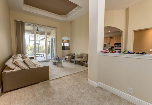 interior space featuring ceiling fan, light tile patterned floors, crown molding, and a tray ceiling