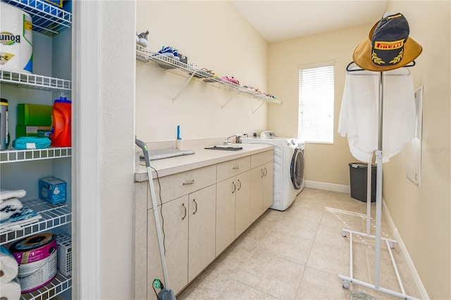 clothes washing area featuring cabinets, light tile patterned floors, and washing machine and clothes dryer