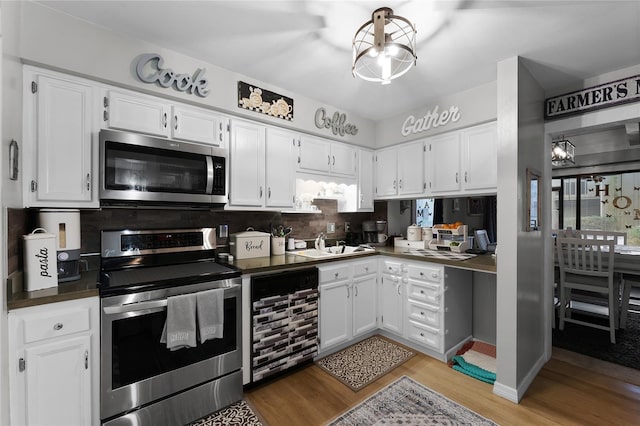 kitchen with light hardwood / wood-style flooring, appliances with stainless steel finishes, white cabinetry, decorative backsplash, and beverage cooler