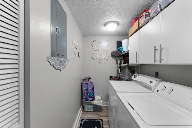 clothes washing area with hardwood / wood-style floors, cabinets, washer and clothes dryer, electric panel, and a textured ceiling