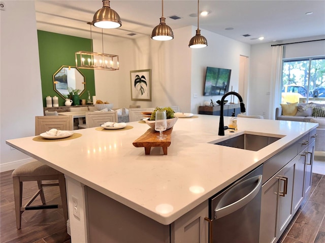 kitchen featuring stainless steel dishwasher, sink, pendant lighting, dark hardwood / wood-style floors, and an island with sink