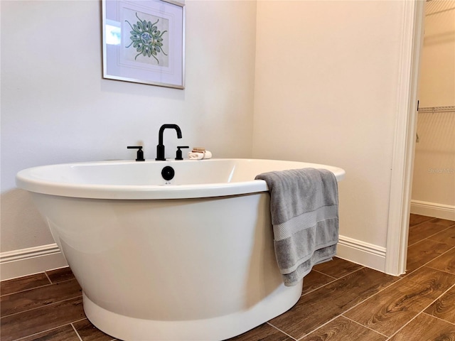 bathroom with a washtub and wood-type flooring