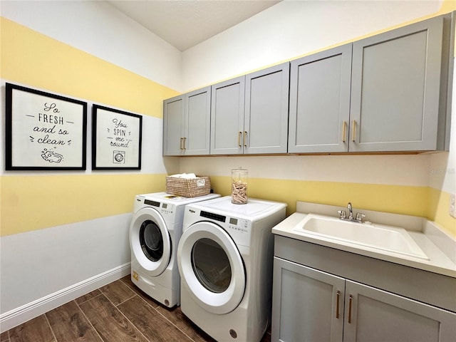 laundry area featuring cabinets, dark hardwood / wood-style flooring, sink, and washing machine and clothes dryer