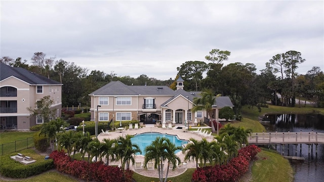 rear view of house with a water view, a fenced in pool, and a patio area