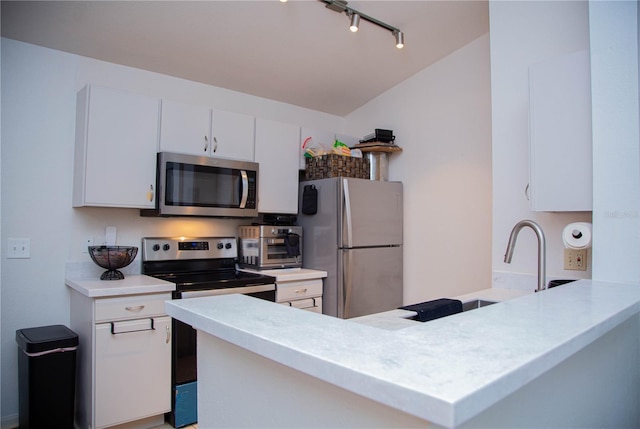 kitchen with lofted ceiling, white cabinets, sink, appliances with stainless steel finishes, and kitchen peninsula