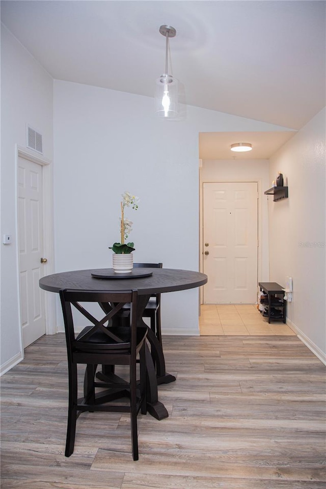 dining area featuring lofted ceiling and light wood-type flooring