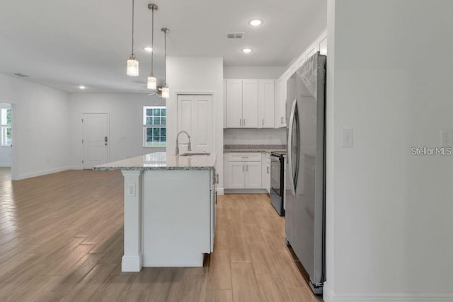 kitchen with white cabinets, light hardwood / wood-style floors, a kitchen island with sink, and appliances with stainless steel finishes