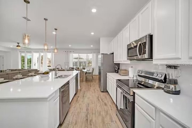 kitchen featuring stainless steel appliances, a kitchen island with sink, a wealth of natural light, and sink