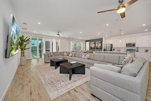 living room with ceiling fan and light wood-type flooring