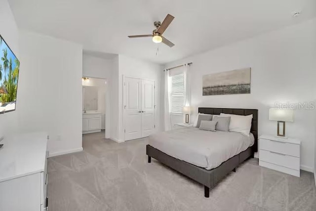 carpeted bedroom featuring ensuite bath, multiple windows, and ceiling fan