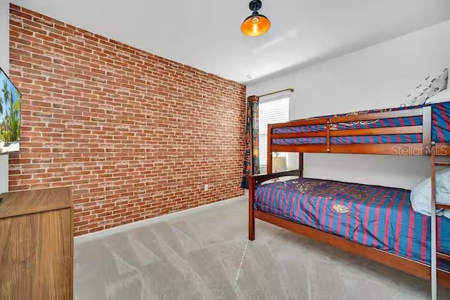 carpeted bedroom with brick wall