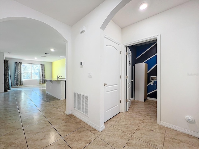 hall featuring light tile patterned floors and sink