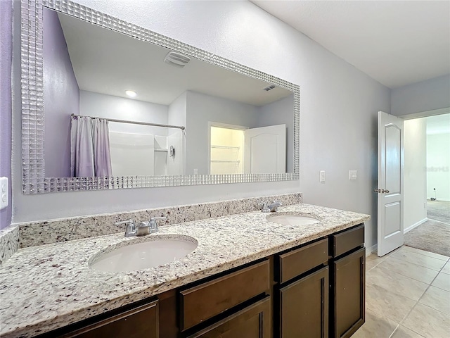 bathroom with tile patterned flooring, vanity, and walk in shower