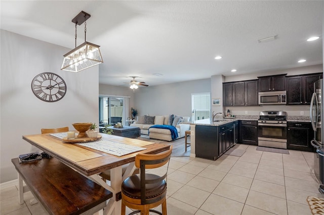 tiled dining area with ceiling fan and sink