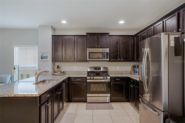 kitchen featuring sink, light tile patterned floors, stainless steel appliances, light stone countertops, and dark brown cabinets