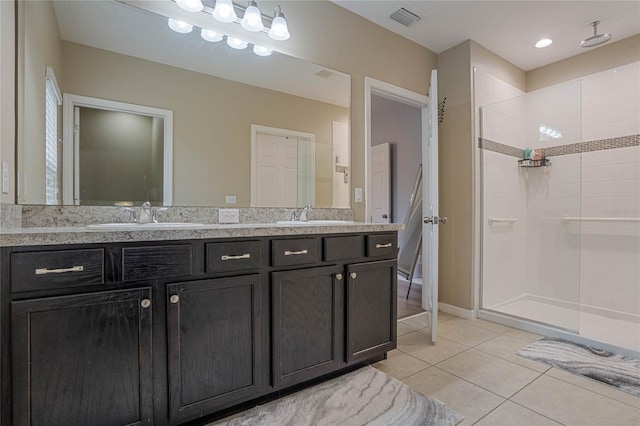 bathroom featuring a tile shower, vanity, and tile patterned flooring