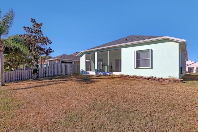 rear view of property with a lawn and a sunroom