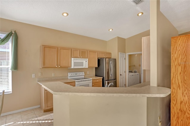 kitchen featuring white appliances, washer and clothes dryer, light tile patterned flooring, light brown cabinetry, and kitchen peninsula