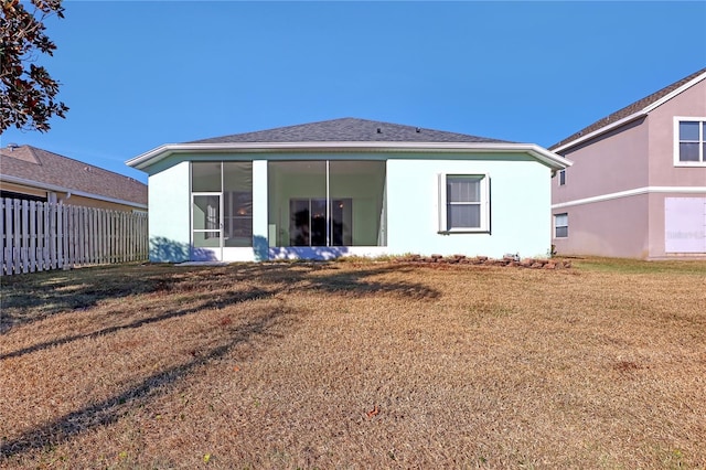 back of house with a sunroom and a lawn