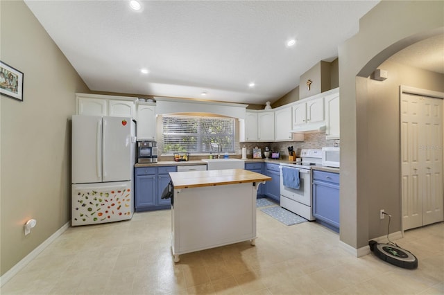 kitchen with white appliances, blue cabinets, butcher block countertops, white cabinetry, and lofted ceiling