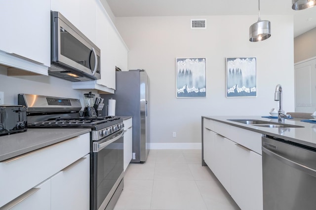 kitchen featuring white cabinetry, sink, hanging light fixtures, stainless steel appliances, and light tile patterned floors